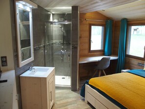 Relax in this cozy retreat with a large bed, shower area, and wooden desk.