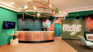 A reception area with a modern design, featuring a central desk, a unique circular light fixture, and a vibrant wall mural. - Rugs Hotel Augsburg, Trademark Collection by Wyndham (Augsburg)