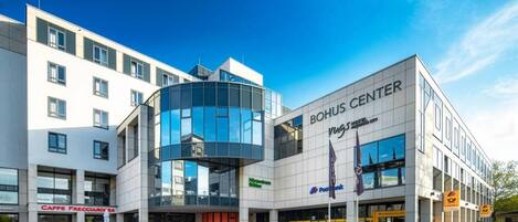 A modern building with a glass facade, a sign for 'BOHUS CENTER,' and a 'CAFFE FRECUROSA' café.