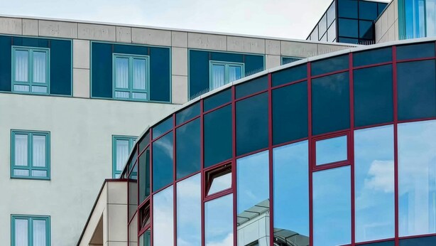 A modern building with a curved glass facade and multiple windows. - Rugs Hotel Augsburg, Trademark Collection by Wyndham (Augsburg)