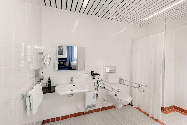 Un baño moderno con un lavamanos, inodoro y ducha blancos.