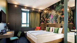 A hotel room with a large bed, a desk with a computer, a chair, and a window with curtains. - Rugs Hotel Augsburg, Trademark Collection by Wyndham (Augsburg)
