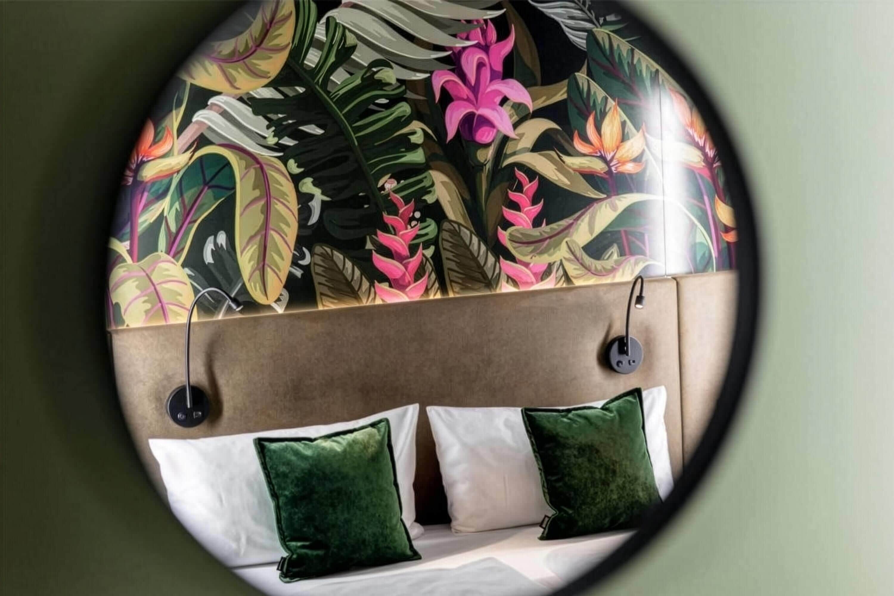 A circular view of a room with a bed, two pillows, and a headboard with a floral mural.