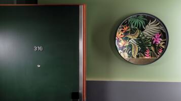 Eine Tür mit der Nummer 310, eine grüne Wand und eine Wanddekoration mit tropischen Blättern und Blumen.