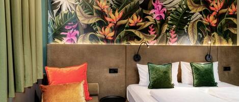 Una habitación de hotel con una cama, un sofá y un mural de follaje tropical.
