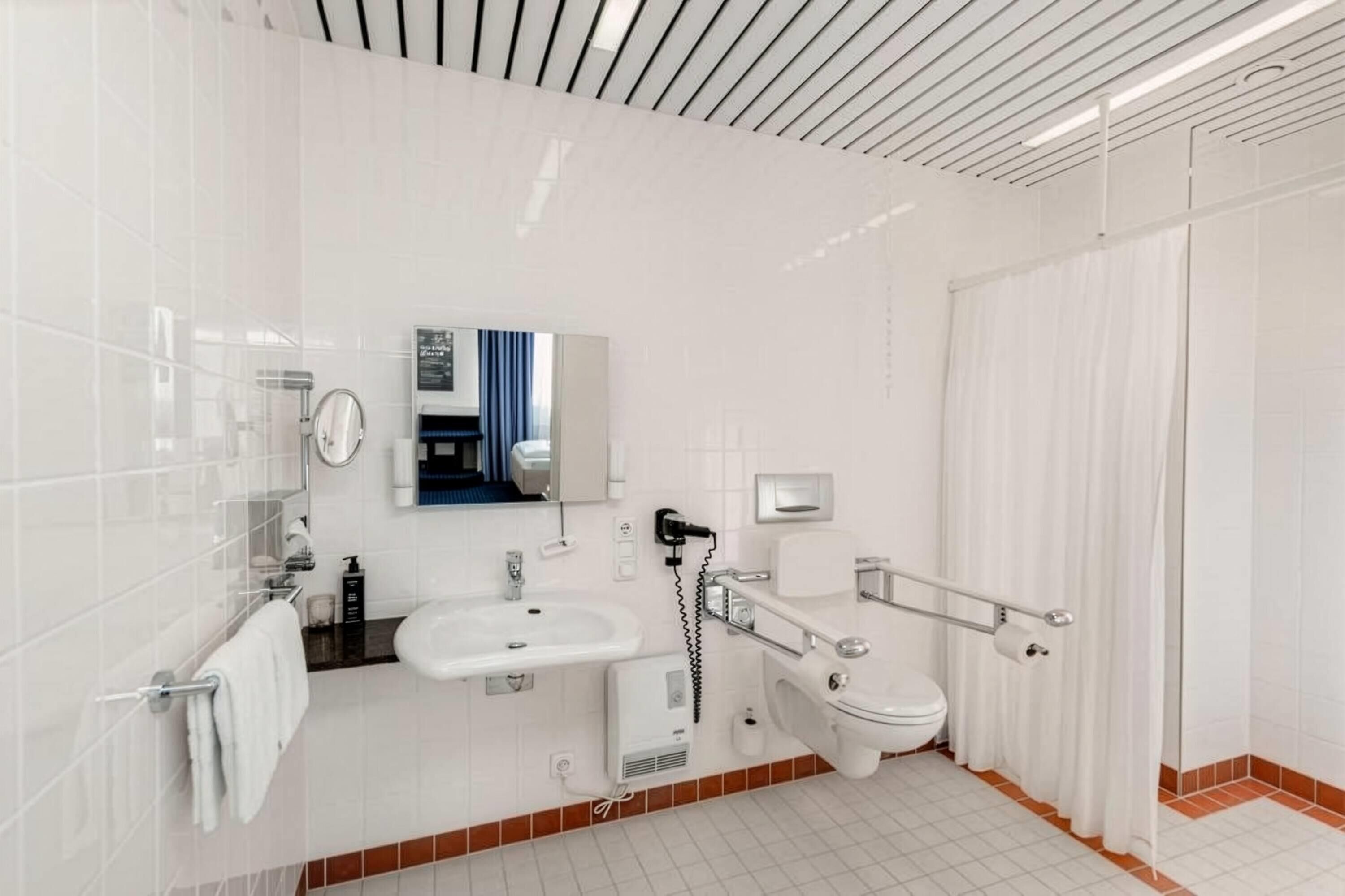 Ein modernes Badezimmer mit Waschbecken, Toilette und Duschbereich in Weiß.