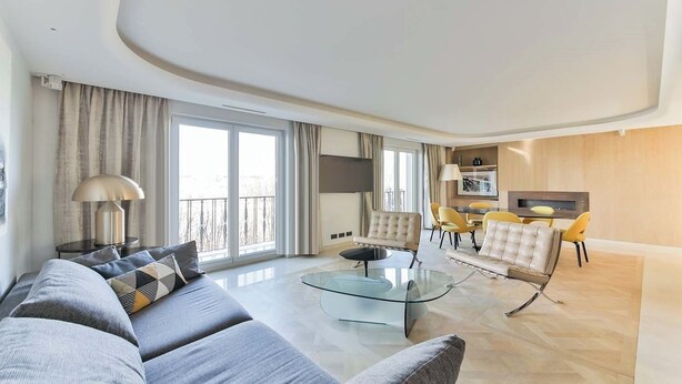 A modern living room with a glass coffee table, grey sofas, and yellow chairs. - QUAINT HIGH-FLOOR RETREAT ON QUAI D'ORSAY – EMBRACE THE PARISIAN LIFESTYLE (Paris)