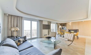 A modern living room with a glass coffee table, grey sofas, and yellow chairs.