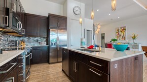 Una cocina moderna con armarios de madera oscura, electrodomésticos de acero inoxidable y una isla grande con un tazón azul.