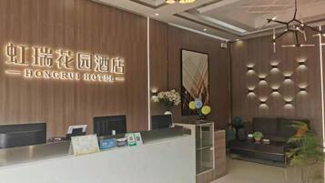 A hotel reception area with a modern design, featuring a reception desk, seating area, and decorative wall panels.