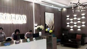 A hotel reception area with a modern design, featuring a reception desk, a seating area with a sofa, and a decorative wall with geometric patterns. - Hongrui Hotel (Anlong)
