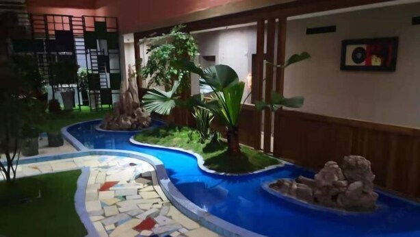 A swimming pool with a mosaic tile design, surrounded by greenery and a small waterfall feature. - Hongrui Hotel (Anlong)