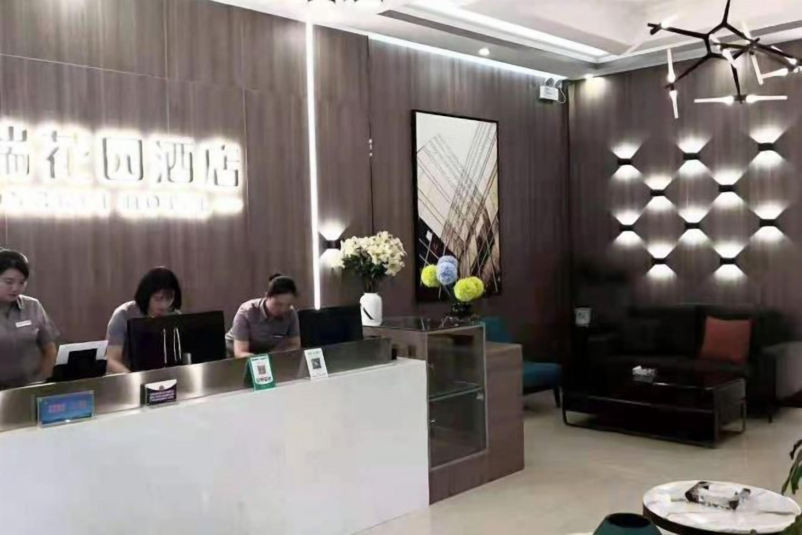A hotel reception desk with staff, a modern interior design, and a seating area with a sofa and a coffee table.