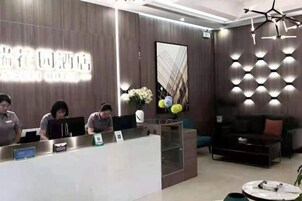 Una recepción de hotel con personal, un diseño de interiores moderno y un área de estar con sofá y mesa de centro.