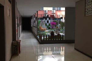Un pasillo con vista a un patio, una cerca decorativa y un edificio al fondo.