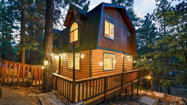 A log cabin with a wooden deck and stairs leading to the entrance.