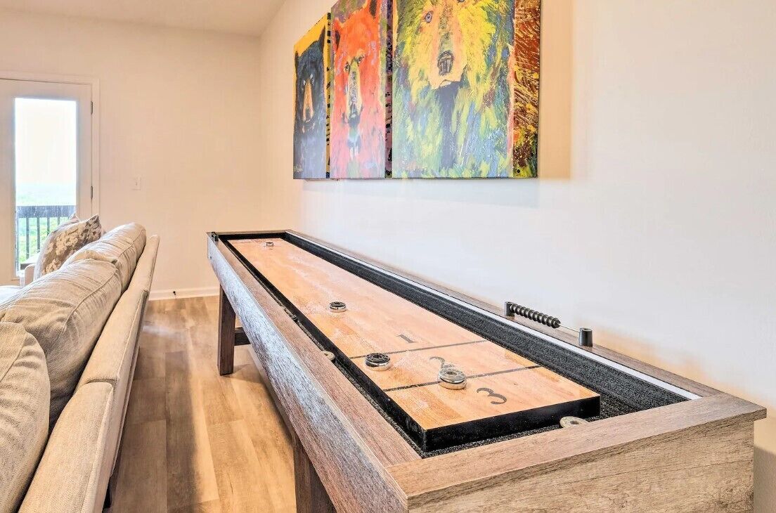 A room with a shuffleboard table, a sofa, and a painting on the wall.