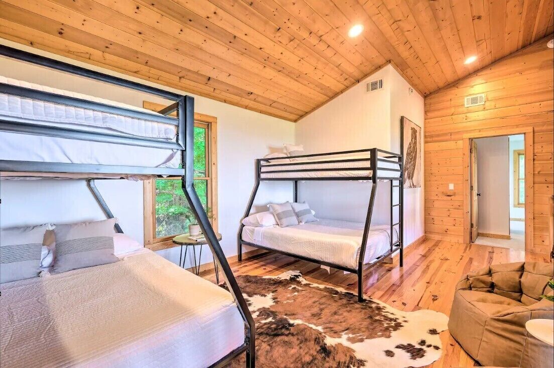 Eine Holzhütte mit zwei Etagenbetten, einem Kuhfellteppich und Holzwänden.