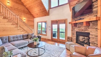 Cozy living area with a high ceiling, fireplace, and flat-screen TV.