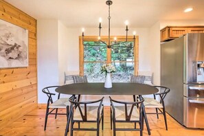A modern kitchen with a dining table, chairs, a chandelier, and a large window with a view of greenery. - Good 2 View Mountain Views Game Room Sleeps 12 (Ranger)