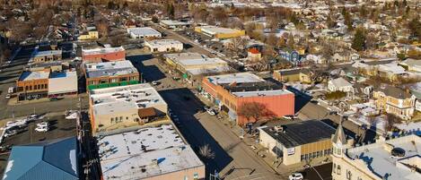 An aerial view of a town with a mix of commercial and residential buildings, including a prominent red building and a large blue-roofed structure.