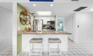 Une cuisine moderne dotée d’un îlot central, d’appareils électroménagers en acier inoxydable et d’un mur d’accent vert.
