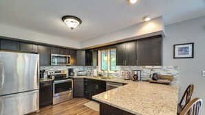 A modern kitchen with dark cabinets, stainless steel appliances, a granite countertop, and a window providing natural light. - Fire Pit! Lake Harmony Home, 3 Mi to Big Boulder (Lake Harmony)