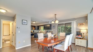 A spacious dining area with a wooden table and chairs, a kitchen in the background, and a view of the outdoors through large windows. - Fire Pit! Lake Harmony Home, 3 Mi to Big Boulder (Lake Harmony)