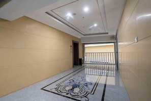 A corridor with a patterned floor, a door at the end, and a railing in the distance. - Dun Huang Shangheyijing Hotel (Dunhuang)
