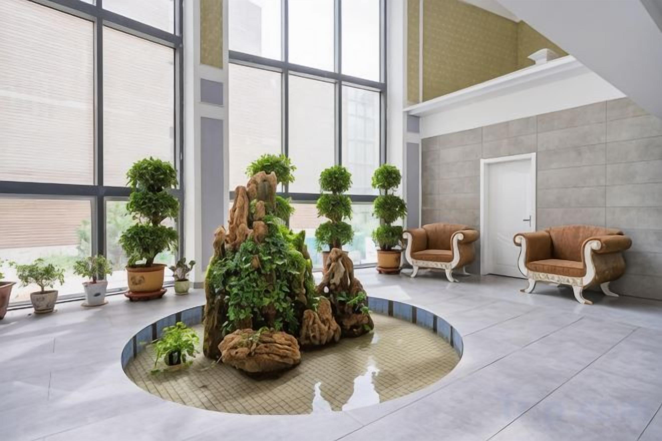 A lobby with a circular seating area, potted plants, and two armchairs.