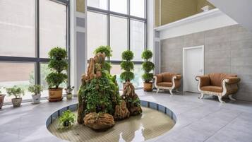 A lobby with a circular seating area, potted plants, and two armchairs.