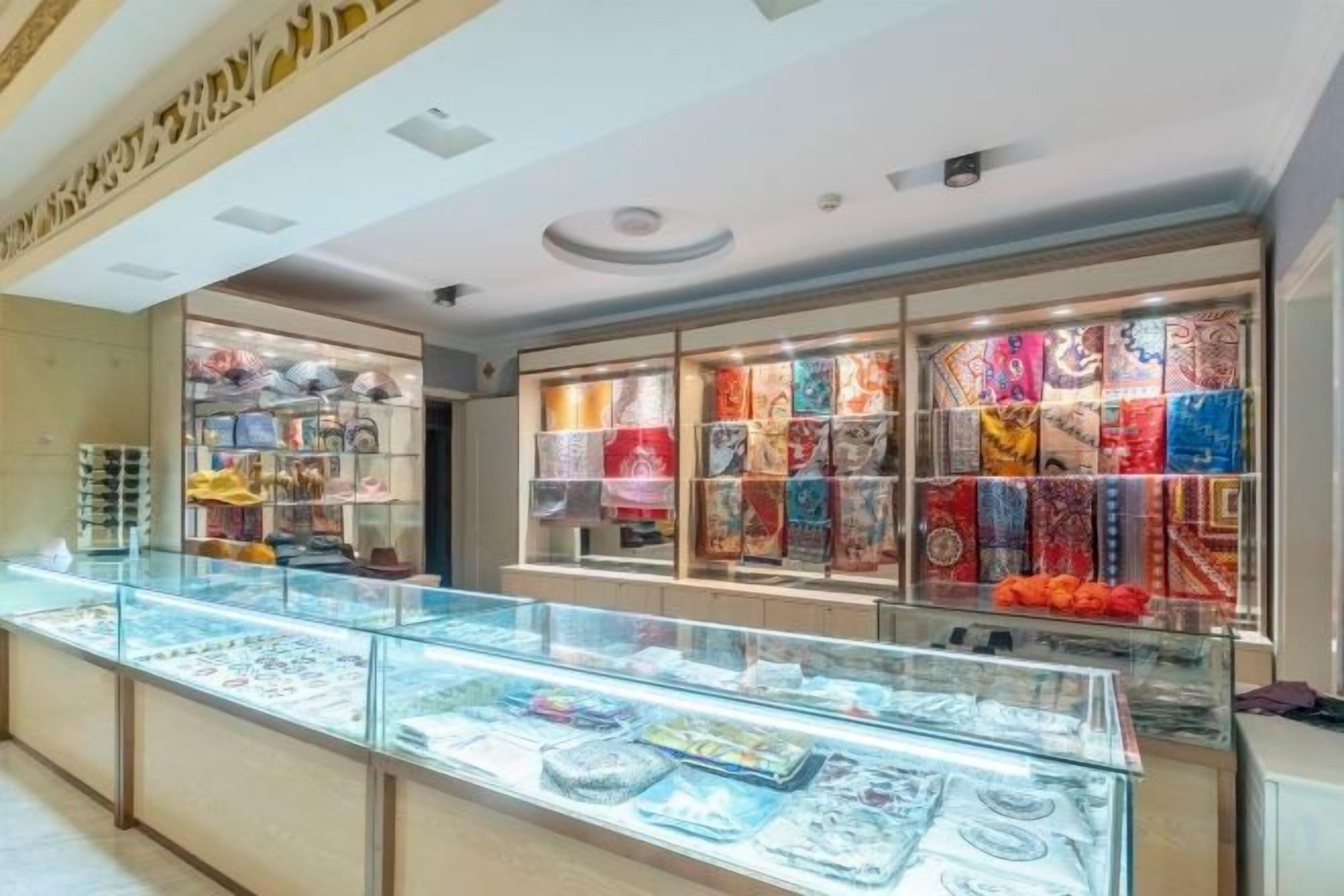 A jewelry display with glass cases and shelves, and a patterned wall in the background.