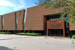 A building with a brick facade and a sign in a foreign language. - Dun Huang Shangheyijing Hotel (Dunhuang)