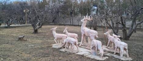 Una escultura de ciervos en un parque, con árboles y una cerca al fondo.