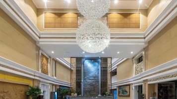 A spacious lobby with a grand chandelier, a reception desk, and a decorative wall.