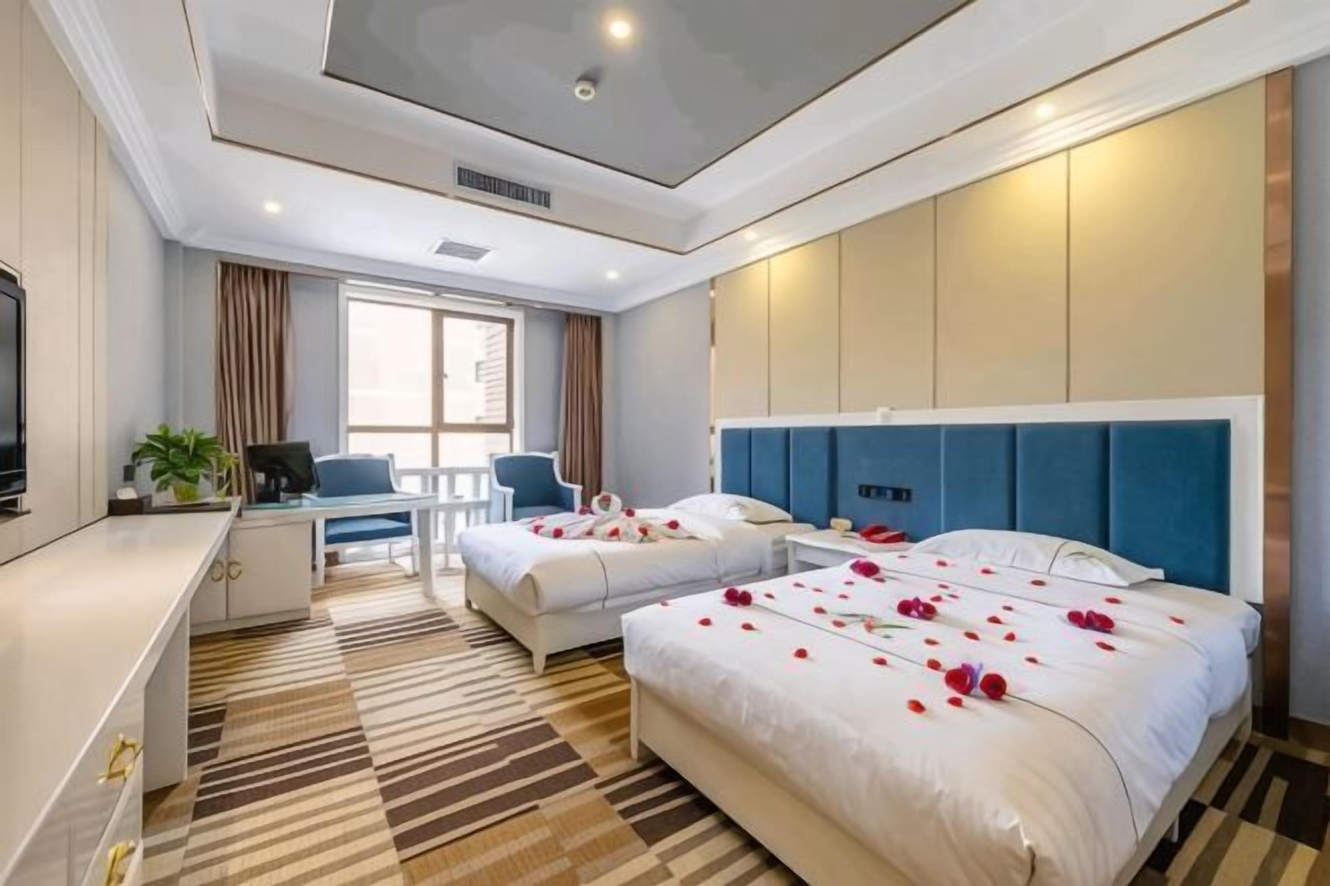 A hotel room with two beds, a desk, a chair, and a television.