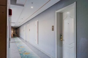 Un long couloir, avec des portes d’un côté et un sol recouvert de moquette.