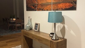 Ein Wohnzimmer mit einer Holzbank, einer Lampe, einem gerahmten Bild und einem Teppich.