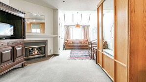 Ein Wohnzimmer mit Kamin, einer Couch und einem Fernseher.