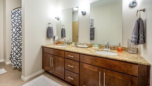A bathroom with two sinks, a large mirror, and a shower curtain.