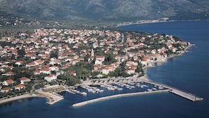 A coastal town with a marina, houses, and mountains in the background.