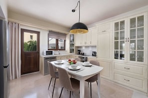 A kitchen with a dining table, chairs, a microwave, and cabinets.