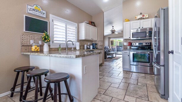 A kitchen with a central island, bar stools, a refrigerator, and a microwave. - Beautiful Home with Private Pool and Tiki Bar. Close to Everything!!! (Surprise)