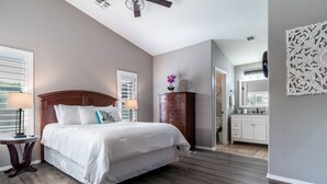 A bedroom with a large bed, wooden headboard, and a dresser. There is a window with blinds and a ceiling fan. - Beautiful Home with Private Pool and Tiki Bar. Close to Everything!!! (Surprise)