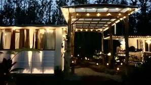 A covered outdoor area with string lights, a wooden pergola, and a small building with windows. - Exotic garden cottage  at amazing volcanic fissure (Mountain View)