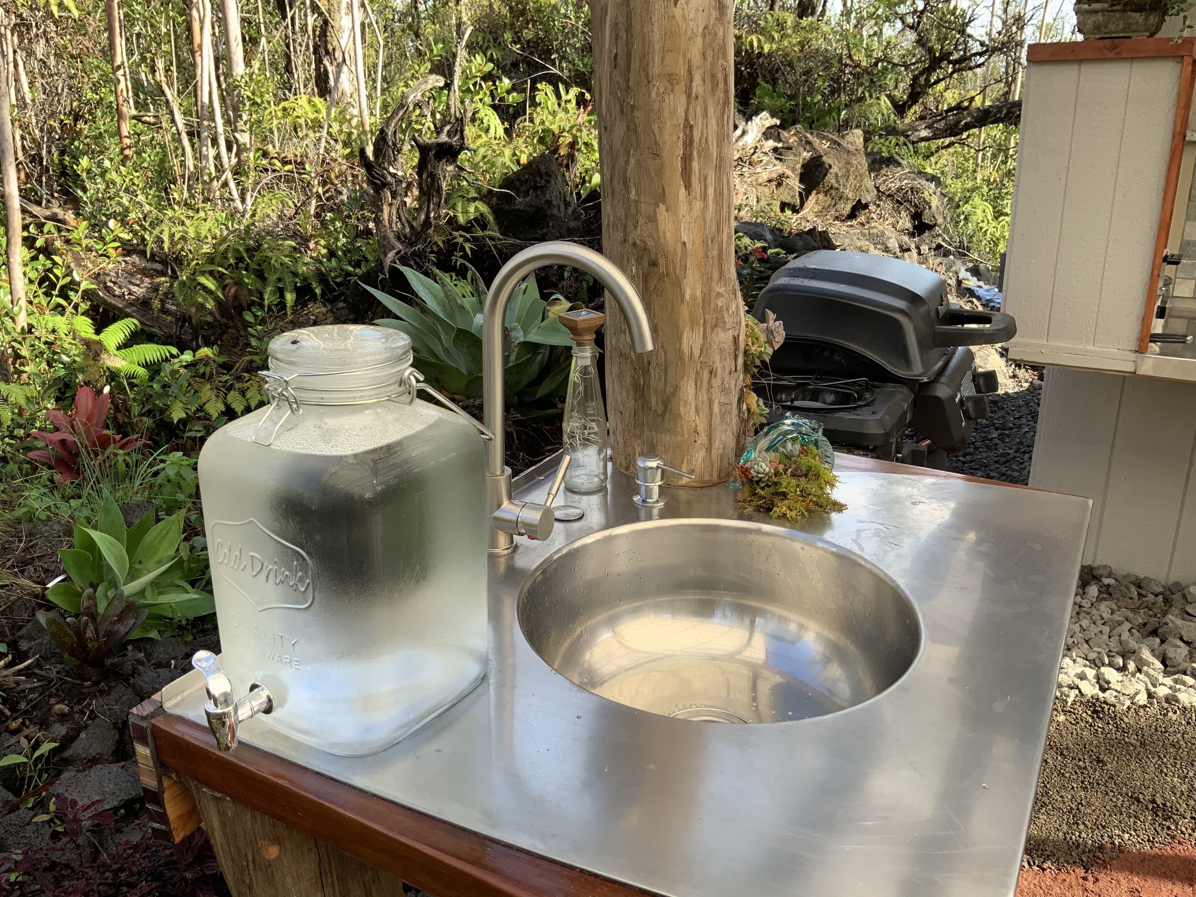 A stainless steel sink with a glass jar labeled "Old Drink" and a faucet.