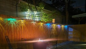 Ein Garten mit Holzlattenzaun, Feuerstelle und einem Stuhl.