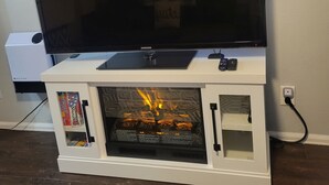 Ein Flachbildfernseher auf einer weißen Unterhaltungsecke mit Kamin darunter.