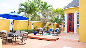 An outdoor patio with a table and chairs, a blue umbrella, and a pool. - Sunlite Studio (Nassau)