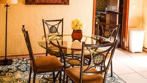 A dining area with a round glass table, metal chairs, a decorative mirror, and a clock on the wall. - Sunlite Studio (Nassau)